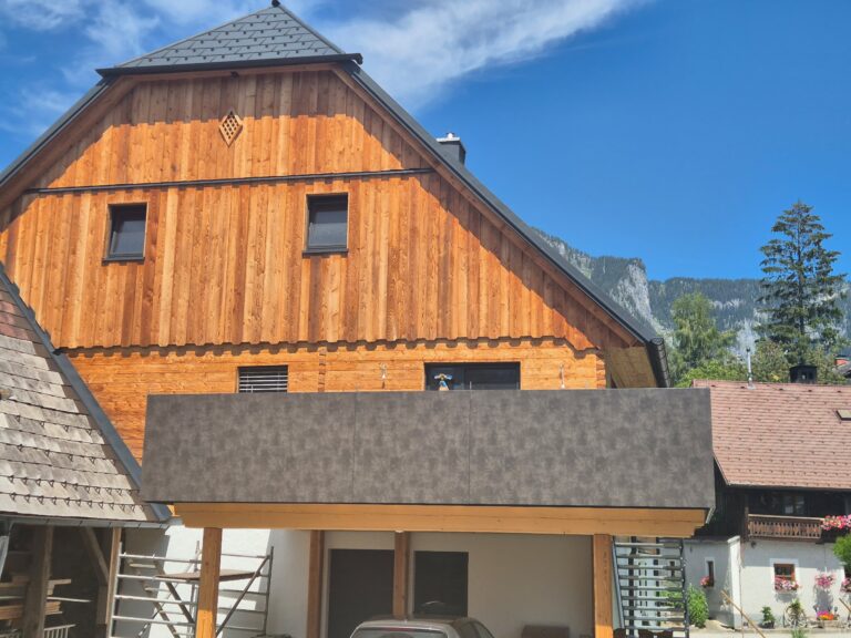Fassade aus naturbelassener Lärche mit gehackter und gebürsteter Blockwandschalung, traditioneller Klingschrotverbindung und sägerauer Lärchenschalung im steirischen Stil.