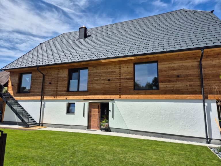 Fassade aus naturbelassener Lärche mit gehackter und gebürsteter Blockwandschalung, traditioneller Klingschrotverbindung und sägerauer Lärchenschalung im steirischen Stil.